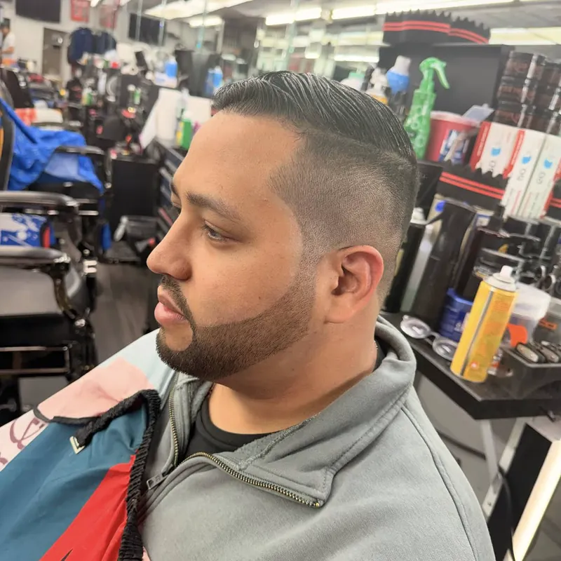 Peinado hacia atrás con fade medio y barba corta perfilada